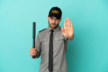 Young security man isolated on blue background making stop gesture
