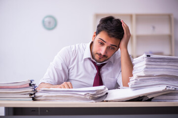 Young businessman employee unhappy with excessive work in the office