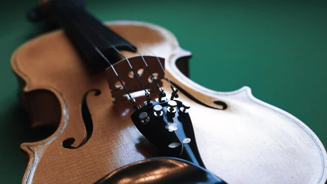 An old beige violin from behind. Dolly shot. Slide shot. Isolated with green background.	

