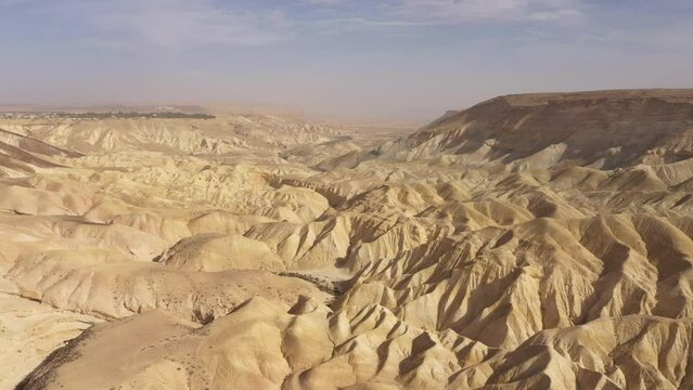 Panoramic drone flight over surreal desert landscape near Sde Boker kibbutz. Dry and rugged mountain scenery in Southern Israel's Negev desert.
