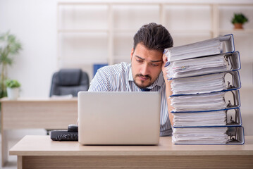 Young male employee and too much work in the office