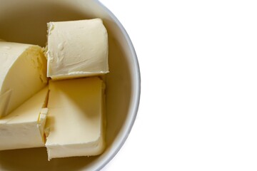 Top view butter pieces in bowl, isolated on white background