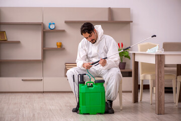 Young male contractor doing pest control at home