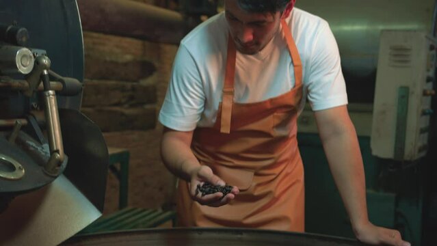 Slow-motion, Men smell and check the quality coffee beans from roasting machines. Young Man half-Asian-caucasian 29 years old working in a factory. Small business owner, coffee roaster