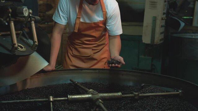 Slow-motion, Men smell and check the quality coffee beans from roasting machines. Young Man half-Asian-caucasian 29 years old working in a factory. Small business owner, coffee roaster
