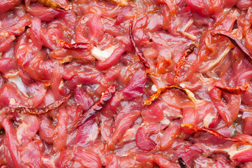 Raw pork meat and dried peppers for cooking.
