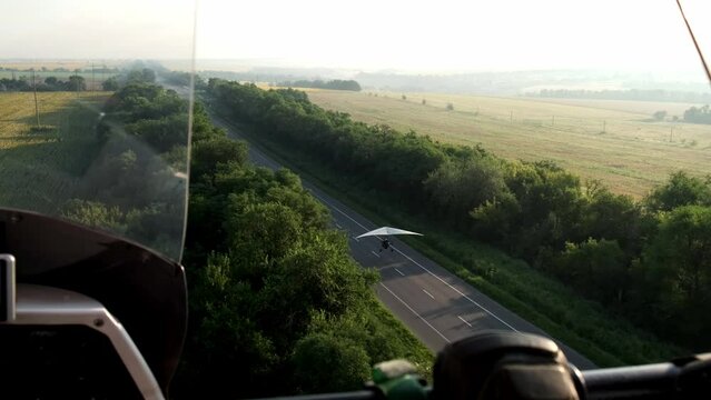 flying on a hang glider with an engine, flying over a paraglider. View from a hang glider. Landing on the road
