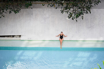 Enjoying suntan and vacation. Top view of pretty young woman in black swimsuit sitting near...