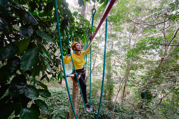 Young woman with climbing gear in an adventure extreme park climbing or passing on the rope road.