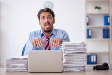 Fototapeta premium Young male employee and too much work in the office