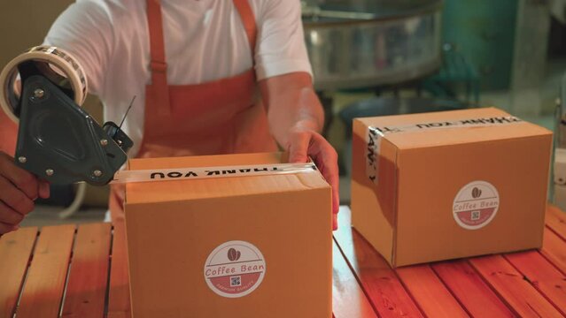 Close up Sealing Cardboard Boxes Ready for Shipment in a coffee factory. Small business owner, brand owner, coffee roaster, industrial