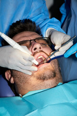 A man with a slight beard undergoing a dental procedure
