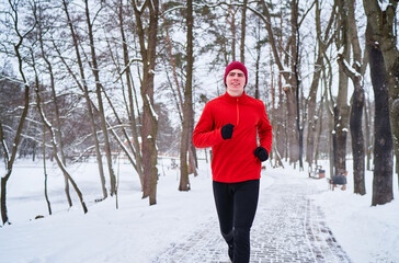 Healthy lifestyle. Jogging outdoors. Young strong man is running at snowy park.