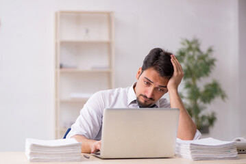 Young male employee unhappy with excessive work in the office