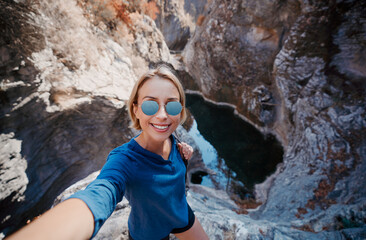 Active lifestyle. Trekking and hiking. Young woman taking selfie in the forest rock canyon.