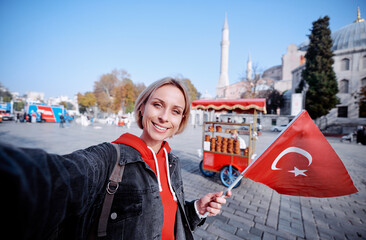 Enjoying vacation in Istanbul. Young traveling woman with national turkish flag taking selfie on...