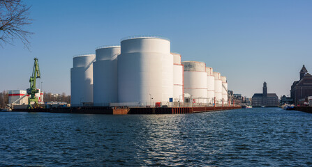 Oil supply. large white steel reservoirs of a tank farm for mineral oil at a canal. 