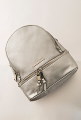Silver backpack, Backpack of silver color on a white background isolate. Small bag with zip front in faux leather and fabric. Urban casual backpack front view.