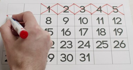 Man's hand Write down the 6,7,8,9,10th day on the paper calendar using a red pen. Very important date in the calendar. Signing a day on a calendar. Calendar date of the month cut.