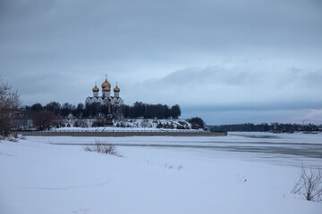 Beautiful snowy field. Frozen river. Church in the distance. Winter nature. Cloudy winter cold day.