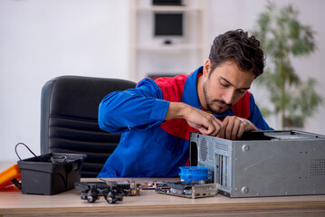 Young male repairman repairing computer