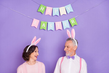 Portrait of two aged persons toothy smile look each other isolated on purple color background