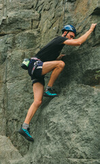Young man in equipment doing rock climbing outdoors. Training area for outdoor activities. Extreme sport.