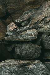 Large pile of stones. Stone rocks. Granite quarry. Abstract background. Abandoned industrial production. Vertical shot.