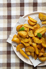Overhead view of potatoes wedges and on white plate