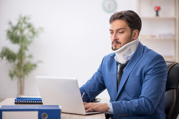 Young neck injured male employee sitting in the office