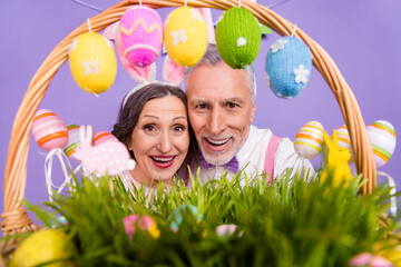 Portrait of two elderly cheerful people toothy smile look camera food basket isolated on purple...