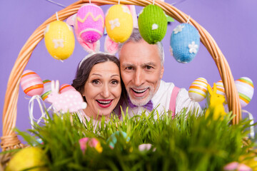 Portrait of two elderly cheerful people toothy smile look camera food basket isolated on purple color background