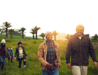 Discovering new places together. Shot of a group of friends walking through a field together.