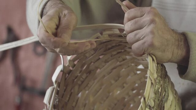 Turkish master weaves baskets from wooden sticks. 4K close-up. Craft concept.