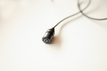 Radio microphone buttonhole on a light background.  Equipment for reporting and videography.