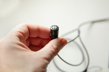Radio microphone buttonhole on a light background.  Equipment for reporting and videography.