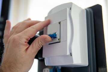 a person turns on a toggle switch with his hand to turn on the light and supply electricity from an electric shield.