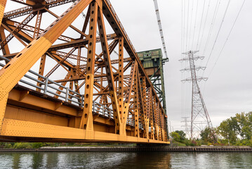 Low angle view of a vertical lift road bridge over a canal. High voltage pylons are visible on the right hand side of the picture.