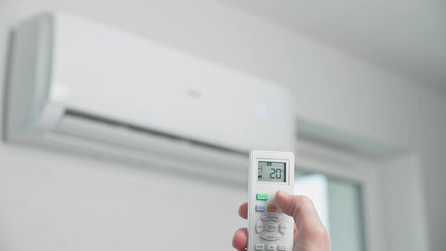 Hand adjusting temperature on air conditioner with remote control, Working air conditioner for comfort temperature in home at hot summer