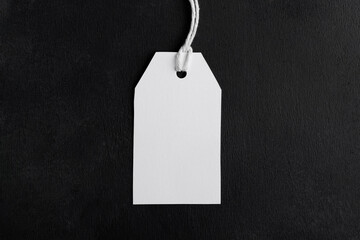 Rectangle white tag mockup with white cord, close up. Blank paper rectangular price tag mockup isolated on black background with copy space, Sale and Black Friday concept