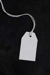Rectangle white tag mockup with white cord, close up. Blank paper rectangular price tag mockup isolated on black background with copy space, Sale and Black Friday concept