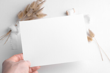 Wedding stationery invitation card mockup 7x5 on white background with boho decor, female hand hold...