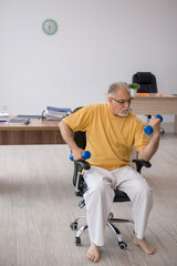 Old businessman employee doing sport exercises in the office
