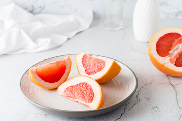 Pieces of juicy fresh grapefruit on a plate on a light table. Vitamin diet food