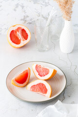 Pieces of juicy fresh grapefruit on a plate on a light table. Vitamin diet food. Vertical view