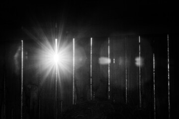 Obraz premium lights shining through wooden stable wall