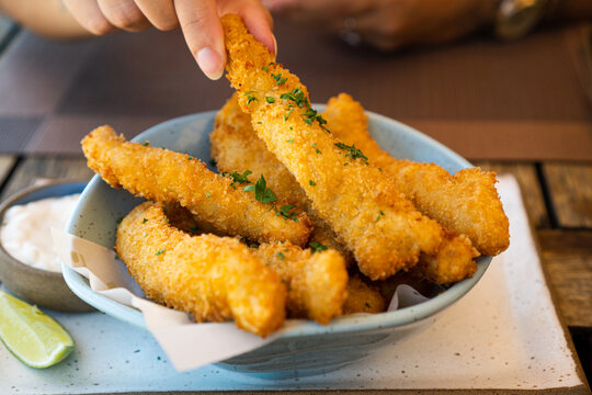 Fresh fried Brazilian tilapia fish strips with lime and tartar sauce known as isca de peixe. Traditional Brazilian appetizer. Selective focus