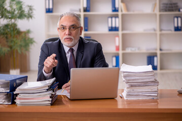 Obraz premium Old male employer and too much work in the office