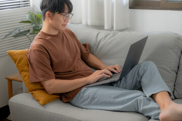 Work at home young asian man working on laptop computer while sitting at home Morning lifestyle