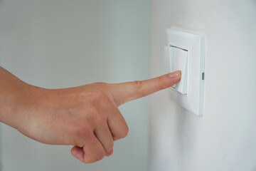 Wastage of Energy. Female finger is turn off on lighting switch.
